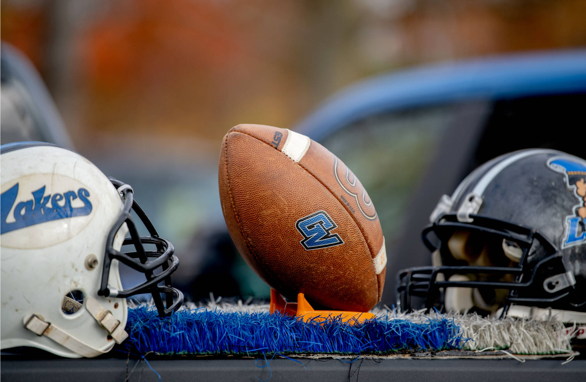 Photo of GVSU football helmets on table with a football in center.
